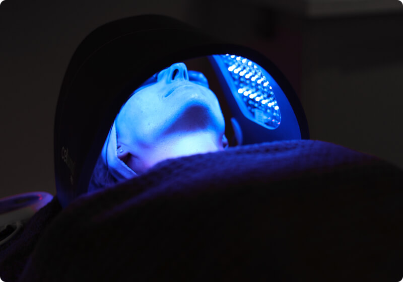 Lady using a LED light therapy treatment on her face